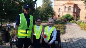 Na zdjęciu policjantka wraz z dziećmi, którym wręczyła kamizelki odblaskowe.