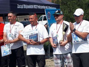 Policjanci odbierający dyplomy i puchary na podium.