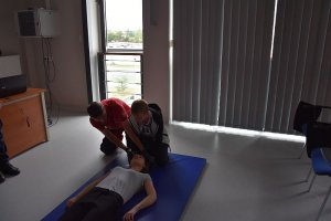 Dwie osoby pochylają się nad osobą leżącą -  pracownik WOPR tłumaczy jak udzielać pomocy.