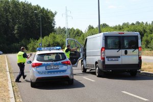 Policjanci z bronią biegną w kierunku zatrzymanego pojazdu