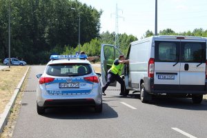 Policjanci z bronią biegną w kierunku zatrzymanego pojazdu