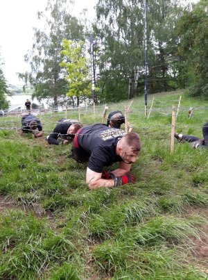 Na zawodach czterech mężczyzn czołga się pod przeszkodą.