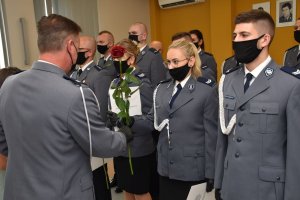 Komendant wręcza różę policjantce, która awansowała na wyższy stopień policyjny.