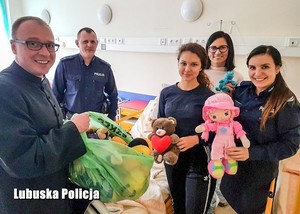 Na zdjęciu policjanci wraz z Kapelanem nowosolskiego szpitala wręczają zabawki chorym dzieciom.