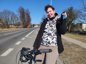 Na zdjęciu kierujący rowerem trzyma w ręku odblaskowego misia.
