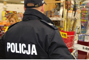Umundurowany policjant kontroluje miejsce sprzedaży fajerwerków.