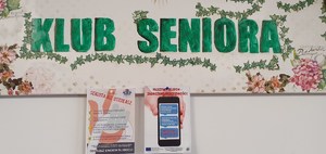 Na zdjęciu gablota Klubu Seniora i ulotki prewencyjne o oszustwach dotyczących seniorów.