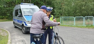 Policjantka wydziału ruchu drogowego kontroluje rowerzystę.