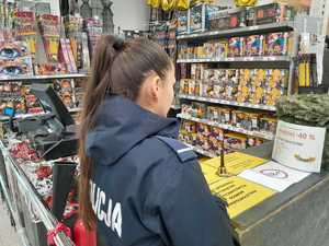 Policjantka kontroluje etykiety ostrzegawcze przy sprzedaży fajerwerków.