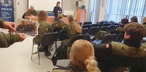 Policjantka prowadzi zajęcia zachęcające do wstąpienia do Policji dla klasy mundurowej.