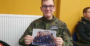 Uczeń klasy mundurowej z ulotką o promocji Policji.