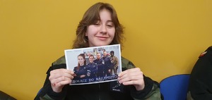 Uczennica klasy mundurowej z ulotką o promocji Policji.