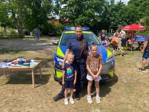 Policjantka z dziećmi na tle radiowozu, podczas rodzinnego pikniku.