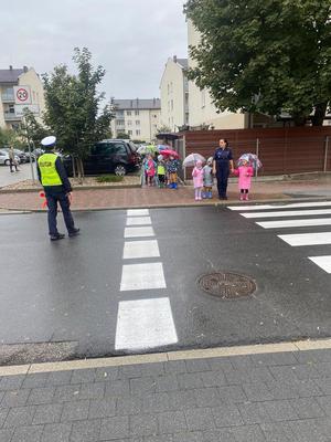 Policjantki uczą dzieci prawidłowego przejścia przez przejście dla pieszych.