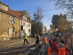 Policjanci z dziećmi przechodzą przez przejście dla pieszych.