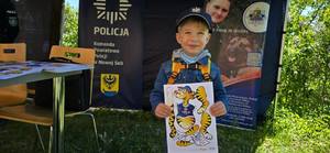 Chłopczyk na tle banera policyjnego.