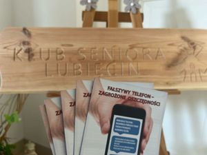 Ulotki policyjne na tle baneru Klubu Seniora w Lubięcinie.