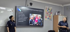 Policjanci na tle prezentacji o rekrutacji do Policji.