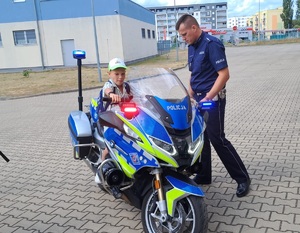 Dzieci robią sobie pamiątkowe zdjęcia na motocyklu policyjnym.