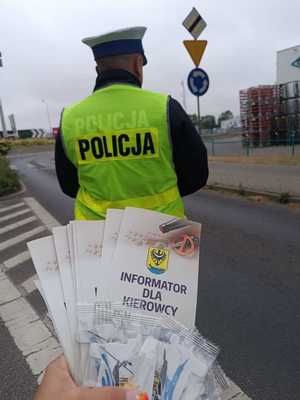 Ulotki informacyjne na tle policjanta sprawdzającego trzeźwość kierowców.