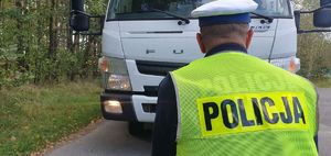 Policjant sprawdza oświetlenie kontrolowanych pojazdów.