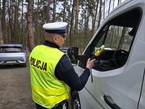 Policjant wydziału ruchu drogowego kontroluje pojazd.